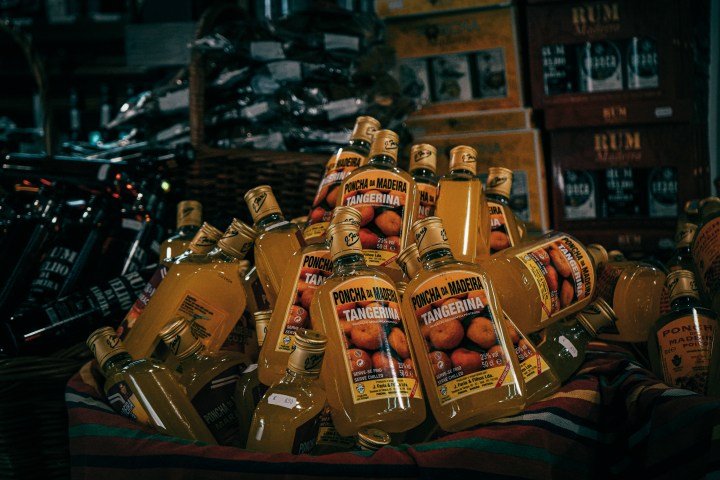 Pile of Poncha da Madeira Tangerine bottles on a striped cloth.