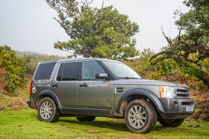 SUV with 'Private Tours' on side parked on grassy terrain near trees.